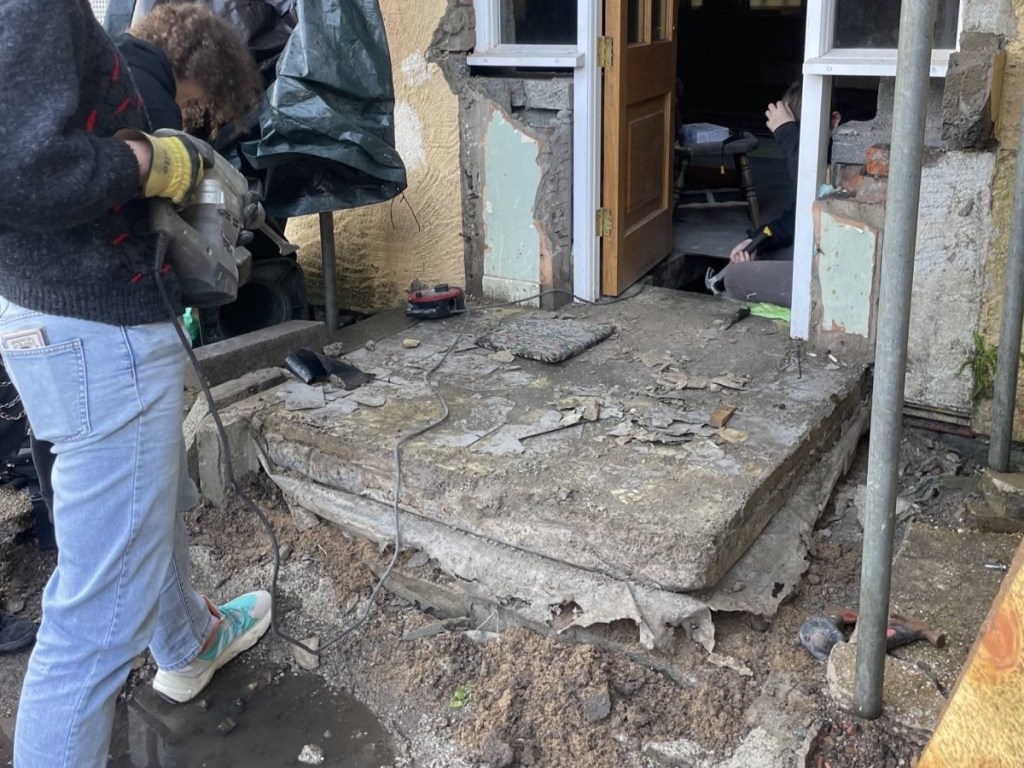 photograph of a huge concrete step and a comrade holding a jackhammer